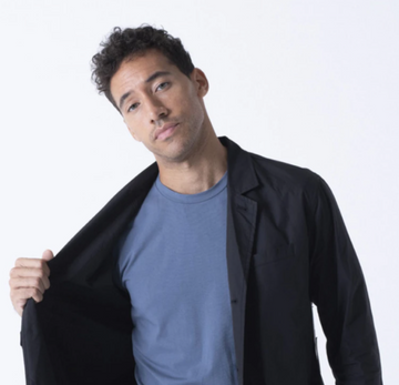 Man opening a black jacket to reveal a blue T-shirt