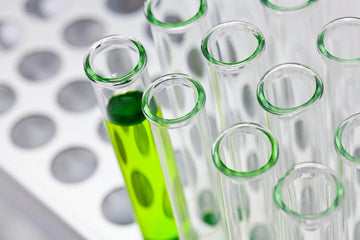 Laboratory test tubes, including one filled with bright green liquid, illustrating body odor research