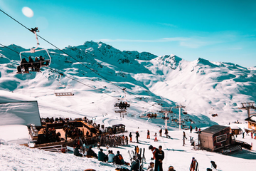 Skiers and snowboarders on a snowy mountain slope beneath chairlifts