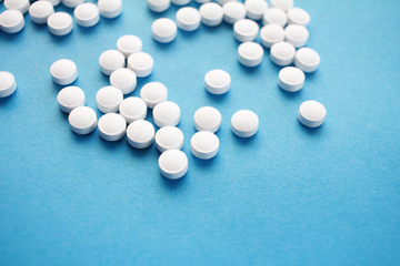 Top view of white oxybutynin tablets scattered across a blue background
