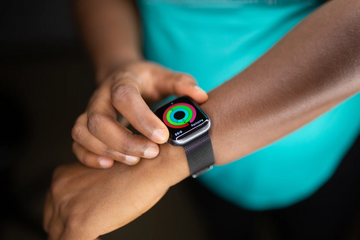 Person checking a smartwatch on their wrist while wearing a turquoise shirt