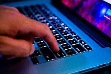 Hand typing on a laptop keyboard while working