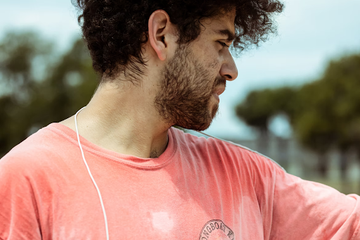 Man wearing a pink shirt with visible sweat stains outdoors