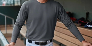 Baseball player standing in a dugout wearing a fitted gray long-sleeve undershirt