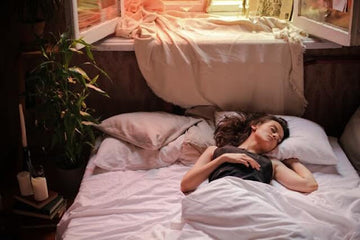 An image of a woman lying in bed and trying to cool down 