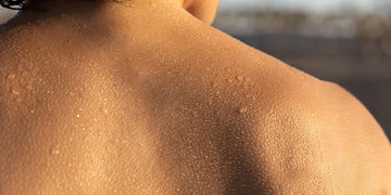 Man sweating with beads of perspiration covering his bare upper back