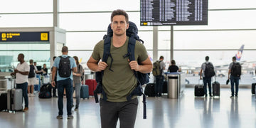Man walking through a crowded airport terminal during travel.