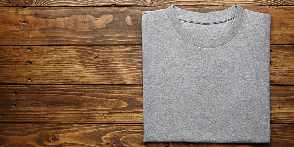 Blank grey t-shirt accurately folded on rustic wooden table top view