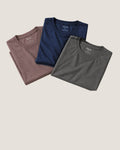 Dusty Clay, Deja Blue and Stone Grey Neat crew necks folded and overlapping on a warm beige background