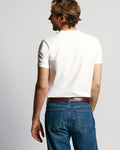 Back view of white V-neck T-shirt on a male model with jeans against a light gray background